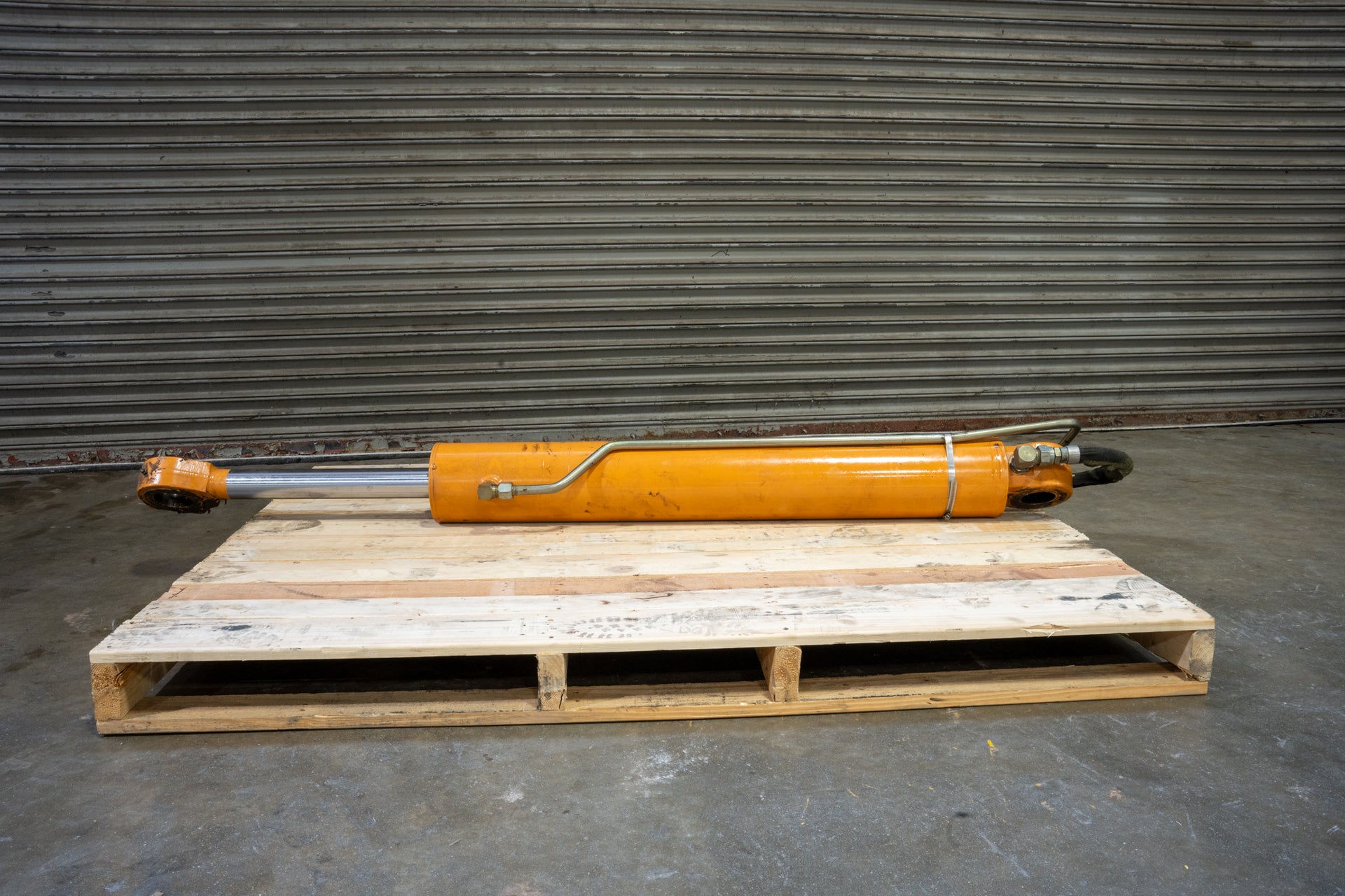 Boom Arm Cylinder 175785A1 on wood pallet in front of garage with hose