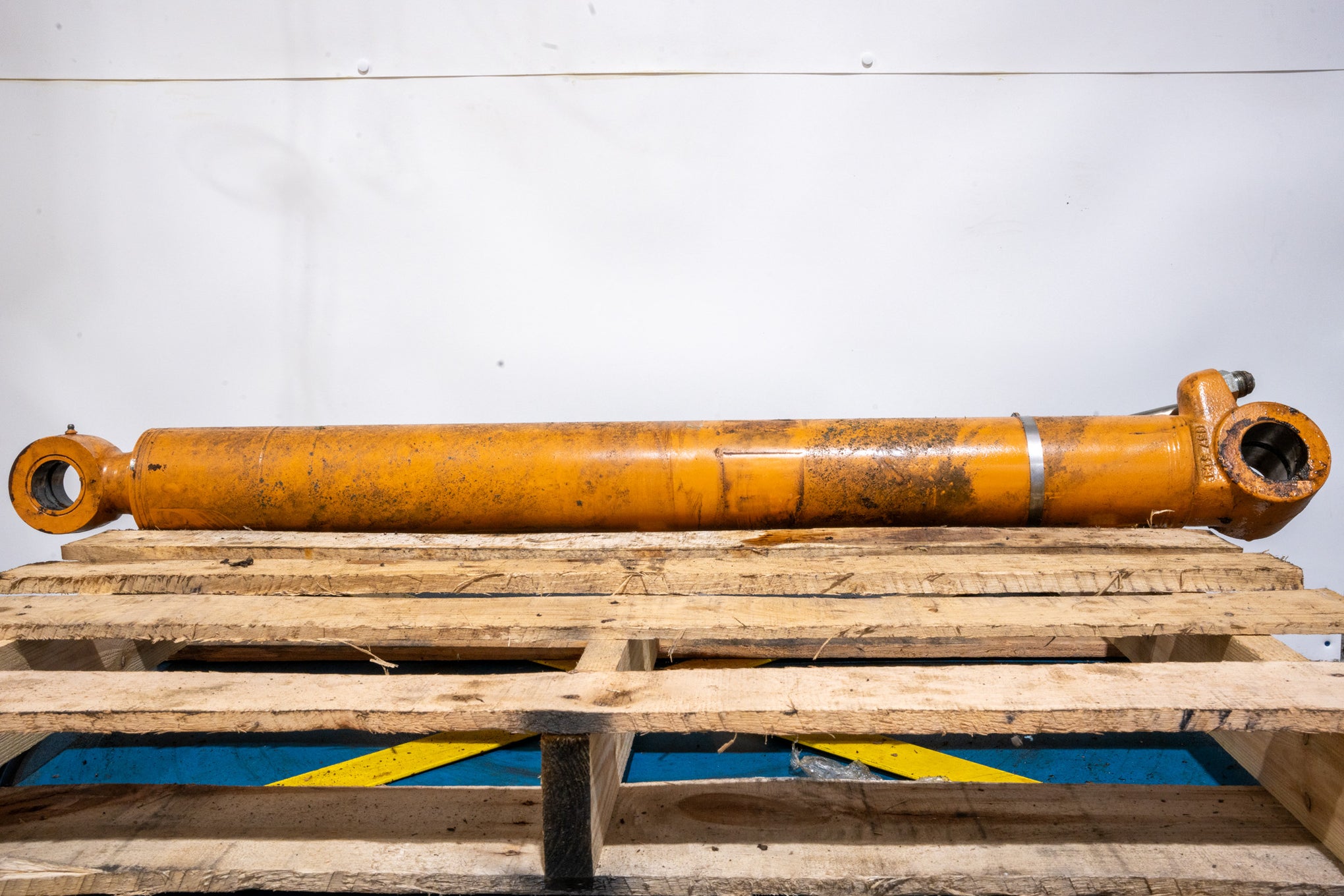 Orange Boom Cylinder from Case Backhoe on wood pallet